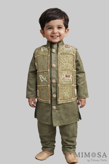 Child wearing a green traditional outfit with a vest on a neutral background