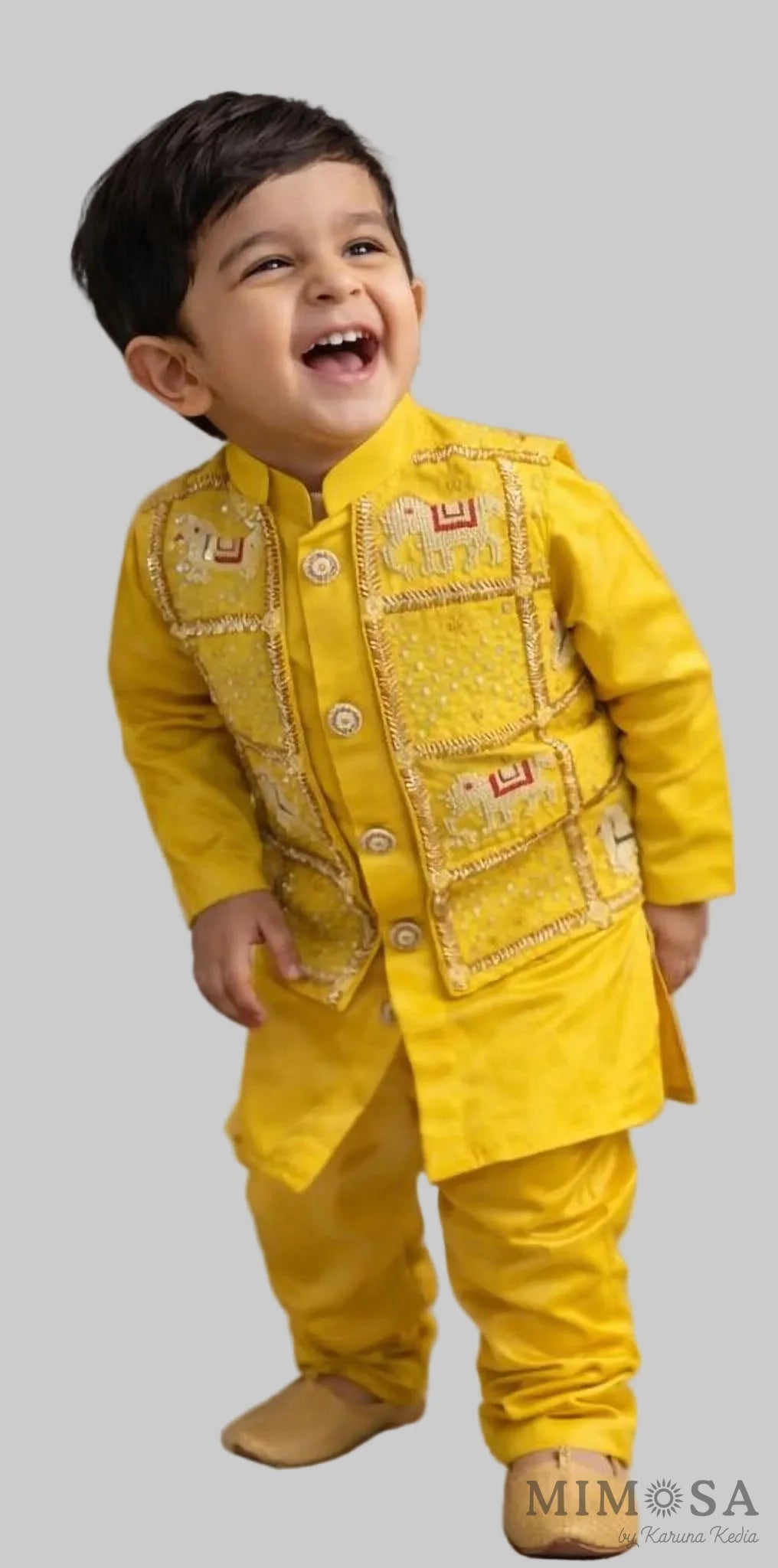 Child wearing a yellow traditional outfit with a smiling expression against a neutral background