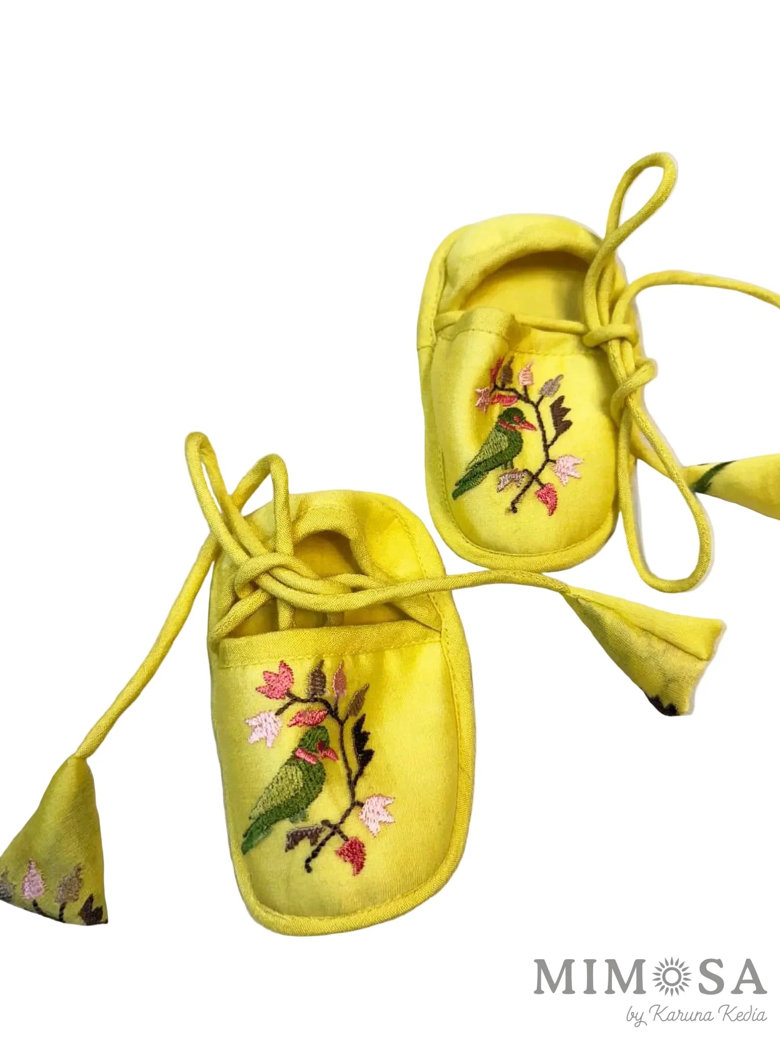 Yellow baby shoes with floral embroidery on a white background